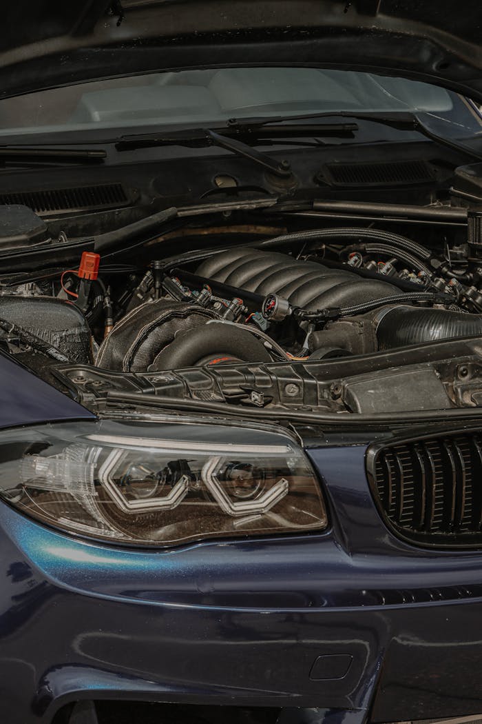 about-06 Detailed view of a car's open engine bay and headlight with focus on mechanical components.
