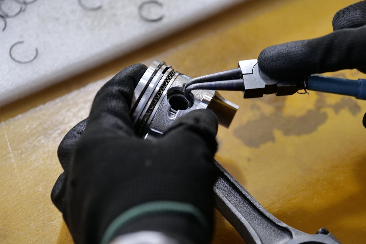 about-03 Gloved hands working on a piston rod in a workshop setting. Industrial repair scene.