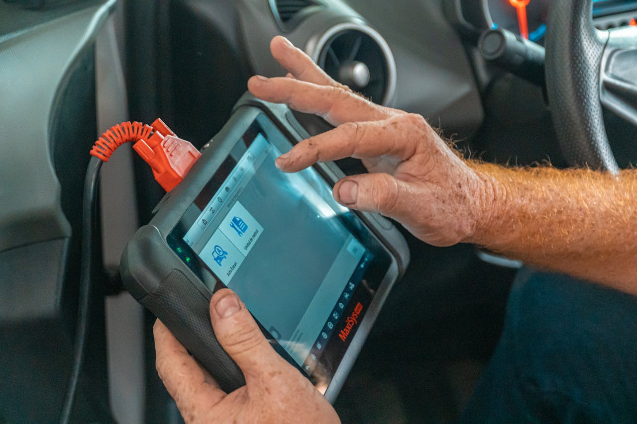 services-10 Mechanic using a diagnostic tool inside a car to check for engine issues and ensure proper maintenance.