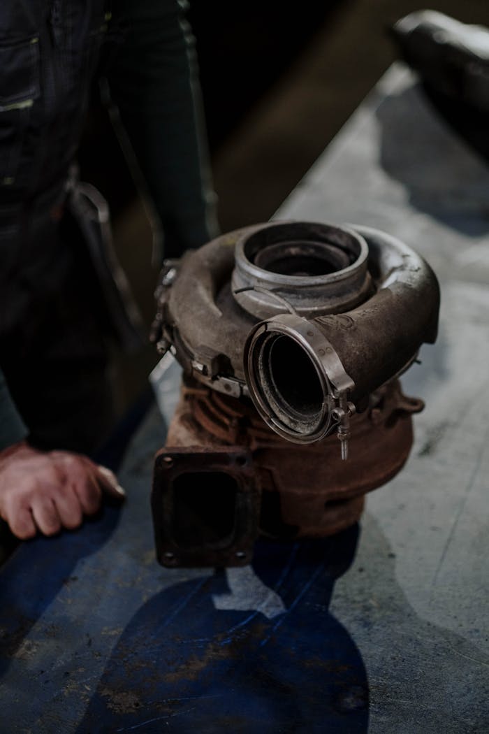 about-07 Close-up of a worn turbocharger on a workbench in an auto repair shop.